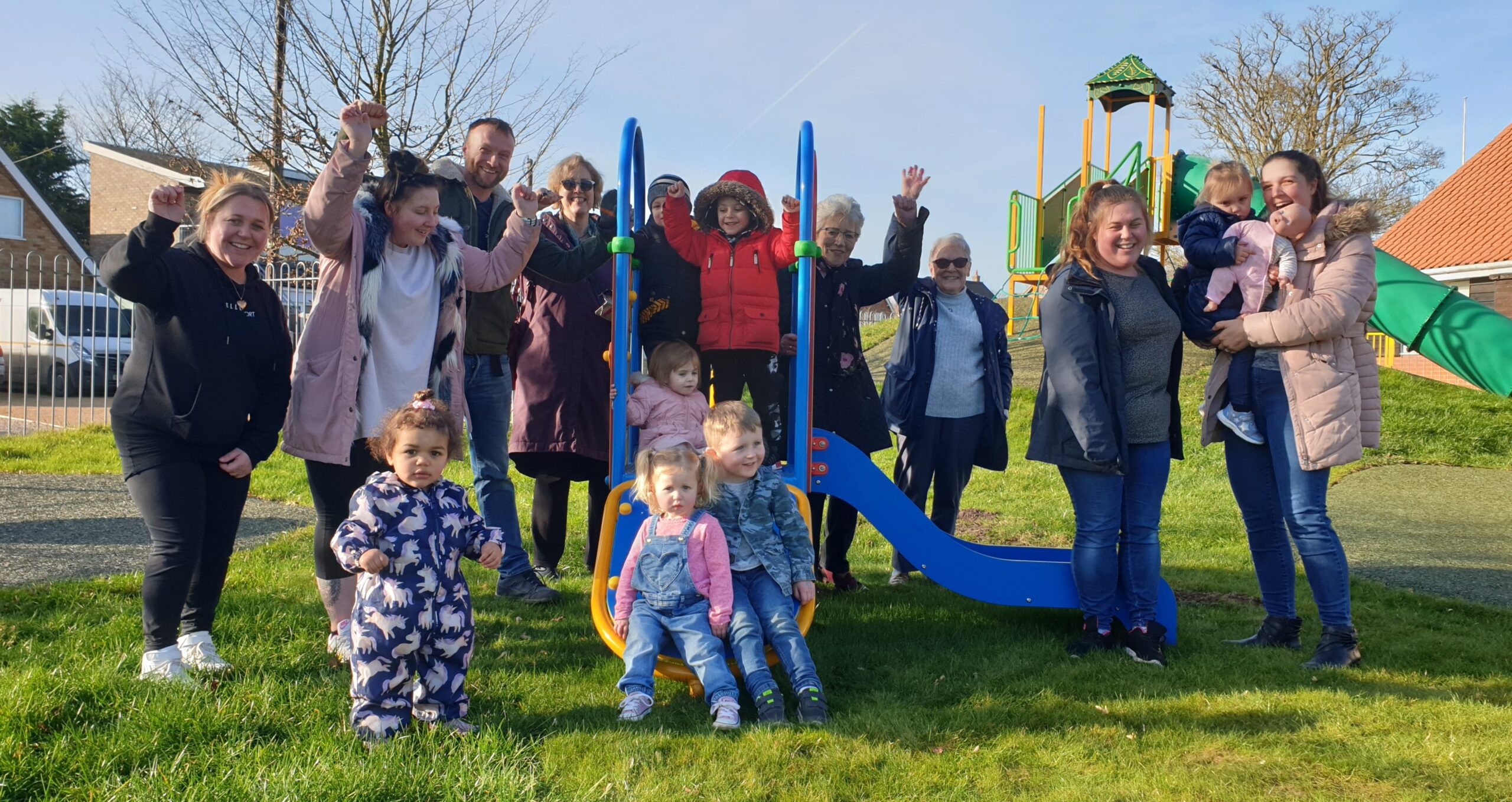 Parents and children celebrating the opening of a new play area at Buxton village hall